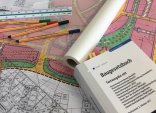 Symbolbild für die Stadtplanung mit Gesetzbuch und Zeichenmaterial