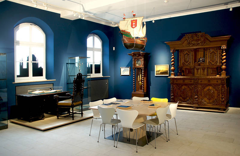 Das Danzig Zimmer Ein Raum mit blauen Tapeten und alten Möbelstücken dekoriert. Von der Decke hängt ein beleuchtetes Segelschiff