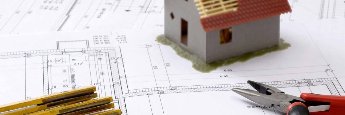 Symbolbild Hausbauplanung mit Zollstock, Zange und Grafik