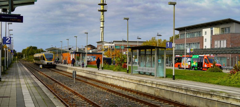 Warendorf Bahnhof Hier ist der Warendorfer Bahnhof mit einem hereinfahrenden Zug sowie Bussen im Hintergrund abgebildet.