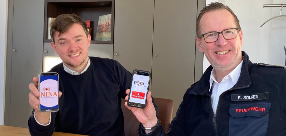 Bürgermeister Peter Horstmann und Frank Sölken, Leiter des Amtes für Brandschutz und Rettungsdienst der Stadt Warendorf, machen auf die Apps „Nina“ und „Nora“ aufmerksam. (Foto: Stadt Warendorf) Bürgermeister Peter Horstmann und Frank Sölken, Leiter des Amtes für Brandschutz und Rettungsdienst der Stadt Warendorf, machen auf die Apps „Nina“ und „Nora“ aufmerksam. (Foto: Stadt Warendorf)